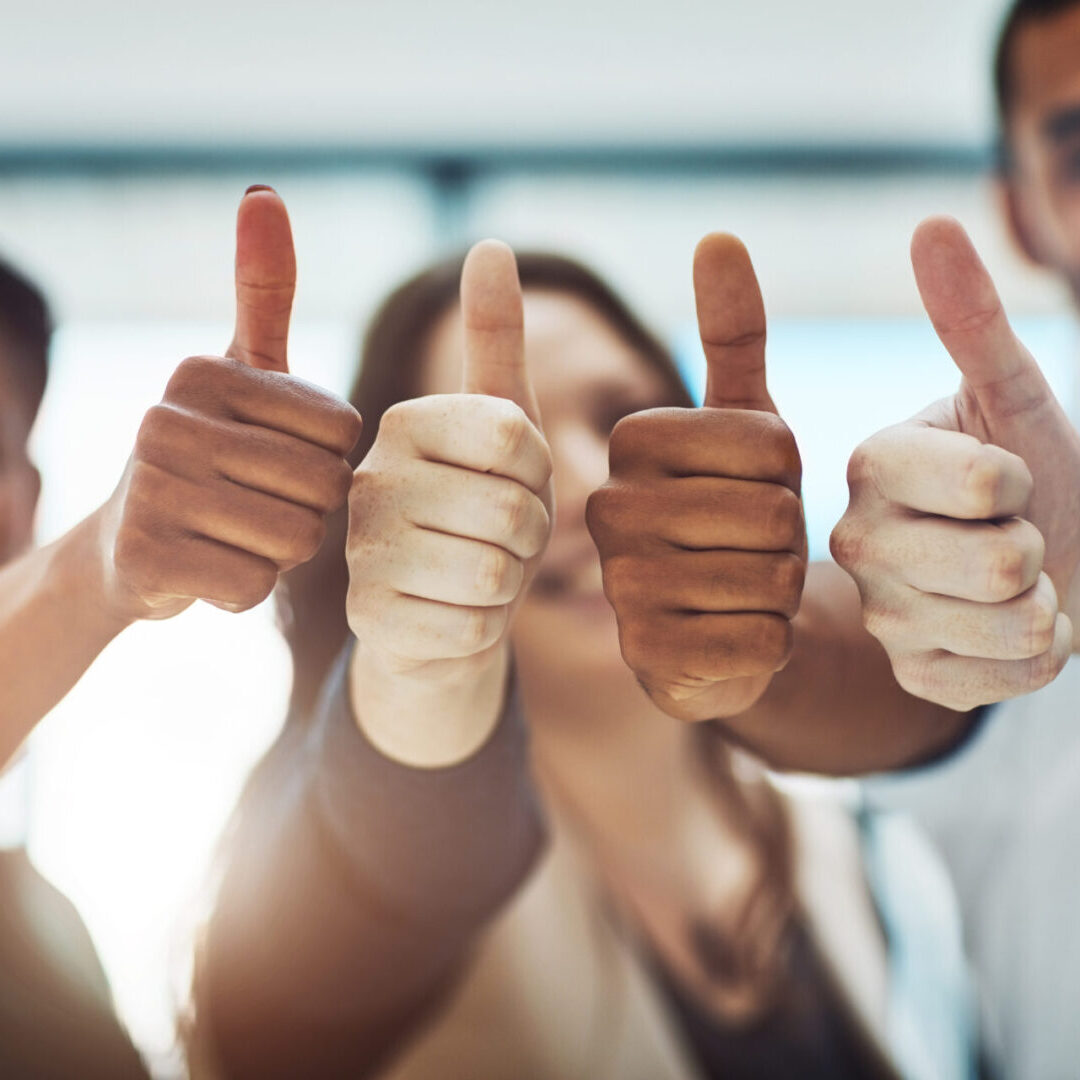 Cropped shot of a team of colleagues showing thumbs up at work