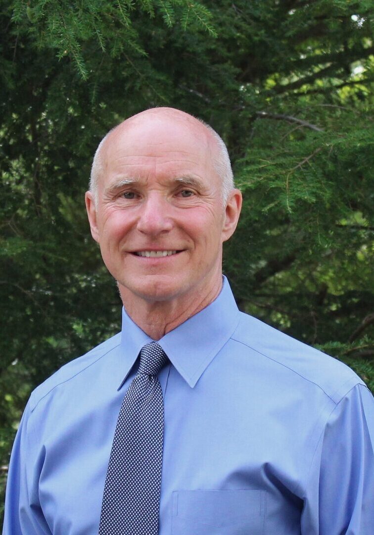 A picture of a man wearing a blue button-up shirt and a dotted tie